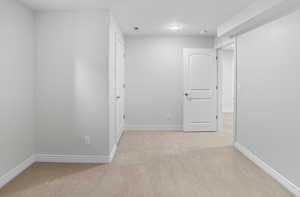 Spare room featuring light colored carpet and baseboards