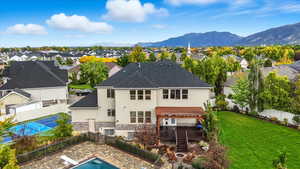 Back of property with a deck with mountain view, stucco siding, stone siding, and a fenced backyard