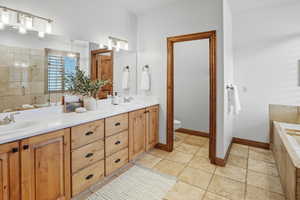 Bathroom with double vanity, a bath, and a stall shower
