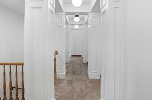Corridor featuring light colored carpet