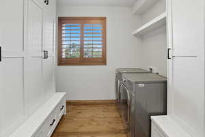 Washroom with light wood-type flooring and washer and dryer
