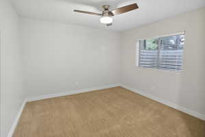 Spare room featuring a ceiling fan and light colored carpet