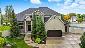 French country home featuring stone siding, a gate, stucco siding, and a garage