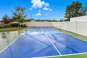 View of tennis court with a patio