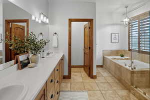 Full bath with a garden tub, double vanity, and a chandelier