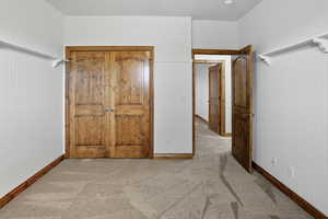 Unfurnished bedroom featuring light carpet and a closet