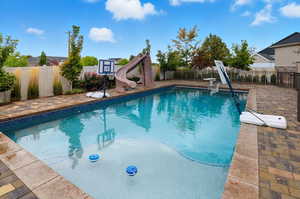 View of pool featuring a fenced backyard, a water slide, and a patio area