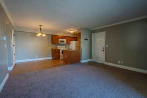 Kitchen with open floor plan, a chandelier, dark carpet, brown cabinetry, and white appliances