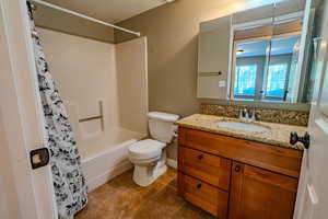 Bathroom featuring vanity, dark tile patterned flooring, shower / bathtub combination with curtain, and a textured wall