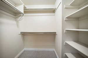 Spacious walk-in closet with light colored carpet