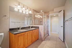 Bathroom featuring light tile patterned floors, a glass shower stall, double vanity, and recessed lighting.