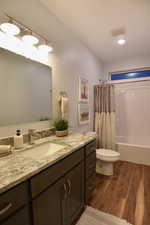 Bathroom with dark wood-type flooring, vanity, shower / tub combo with curtain, and recessed lighting