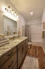 Full bath with shower / bathtub combination with curtain, dark wood-style floors, and vanity