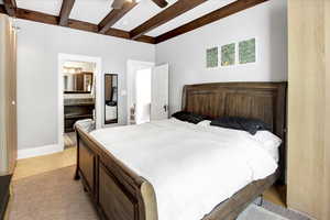 Bedroom with beamed ceiling, a ceiling fan, ensuite bathroom, and light wood-style floors