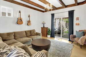 Living area with wood finished floors, beamed ceiling, and a chandelier