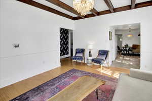 Living area featuring a chandelier, wood finished floors, and beamed ceiling