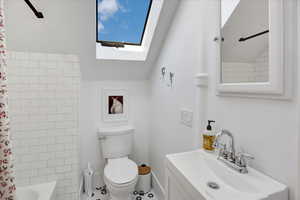 Bathroom featuring shower / bath combo, a skylight, vanity, vaulted ceiling, and tile patterned floors