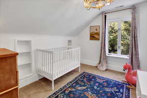 Bedroom with a chandelier, light carpet, and vaulted ceiling