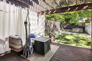 Wooden terrace with a fenced backyard, a hot tub, and a pergola