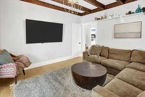 Living room with wood finished floors, beam ceiling, and a chandelier