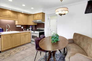 Kitchen featuring range with gas cooktop, recessed lighting, light countertops, decorative light fixtures, and ornamental molding