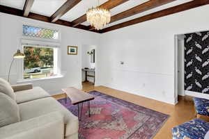 Living area with wood finished floors, beamed ceiling, and a chandelier