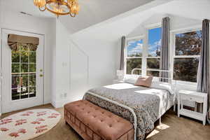 Carpeted bedroom featuring a chandelier, multiple windows, access to outside, and lofted ceiling