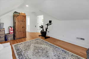 Exercise room featuring lofted ceiling, light wood-style floors, and recessed lighting