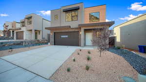 Contemporary house featuring stucco siding, driveway, stone siding, and a garage
