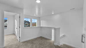 Hall with an upstairs landing, light colored carpet, and recessed lighting