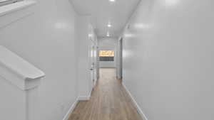 Hall with light wood-style floors and recessed lighting