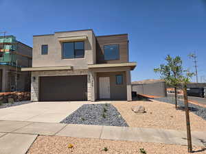 Contemporary house featuring stucco siding, driveway, stone siding, and a garage