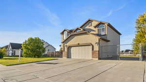 Traditional home with a gate, driveway, a garage, brick siding, and stucco siding