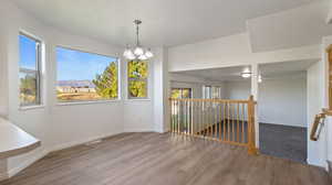 Unfurnished dining area with wood finished floors and a chandelier