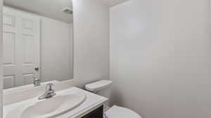 Half bath with vanity and a textured ceiling