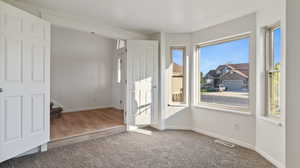 Carpeted spare room featuring baseboards and stairs