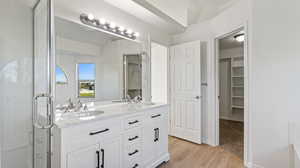 Bathroom with light wood-type flooring, double vanity, a walk in closet, and a shower stall