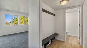 Mudroom with a textured ceiling and light wood-type flooring