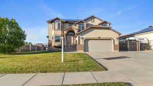 View of front of property featuring solar panels, brick siding, driveway, stucco siding, and a gate