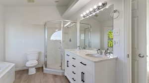 Bathroom featuring light wood-style floors, double vanity, a stall shower, and a garden tub