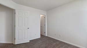 Unfurnished bedroom featuring dark colored carpet and baseboards