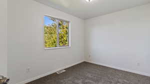 Spare room with dark carpet and baseboards