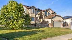 View of front of home featuring stucco siding, a front lawn, brick siding, and driveway