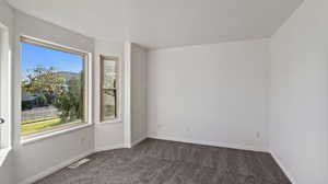 Spare room with dark carpet and baseboards