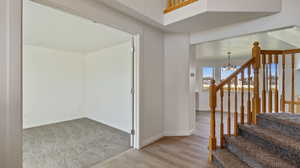 Stairs with a chandelier and wood finished floors