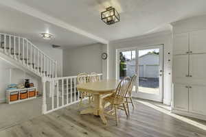 Dining room with light wood finished floors, crown molding, and stairs