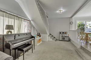 Living area featuring stairs and light carpet