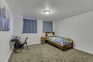 Carpeted bedroom featuring a textured ceiling and baseboards