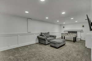 Living area with a decorative wall, light colored carpet, recessed lighting, and a wainscoted wall