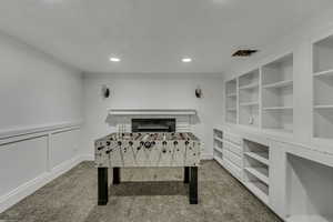 Rec room with light colored carpet, recessed lighting, crown molding, a decorative wall, and a wainscoted wall